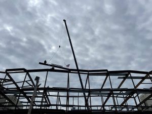 A crane drops the ceremonial final steel beam into place at the Driscoll School Topping Off