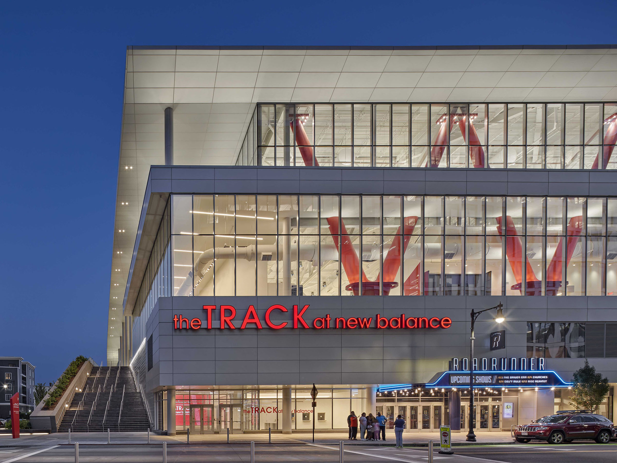 Exterior night view of The TRACK at New Balance, illuminated with red