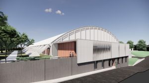 Modern multi-level building with white arched roof and exposed supports, featuring mixed material facade and landscaped surroundings.