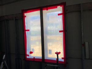 Newly installed window showing red air-sealing tape around frame and protective covering in place.