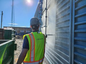 LeMessurier engineer surveying the exterior of a corregated metal building being sprayed by water during testing.