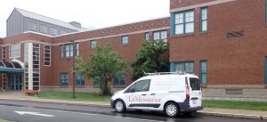 Reeds Brook Middle School exterior with turquoise-framed windows and LeMessurier service van parked in front.